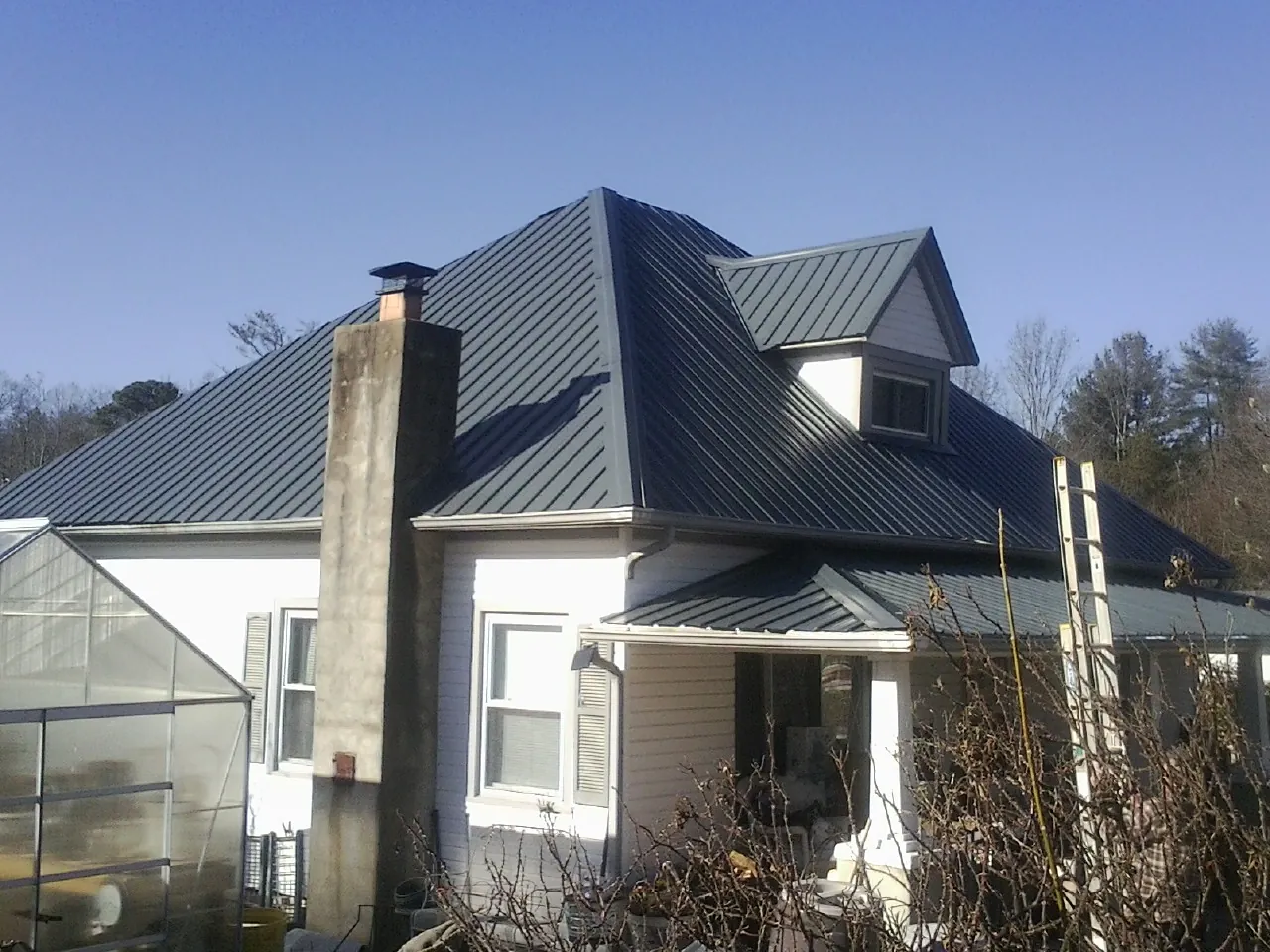 Dark blue standing seam metal roof on a white farmhouse with dormer — Slate & Tile Roof Repair by Roofing Brothers in Highspire