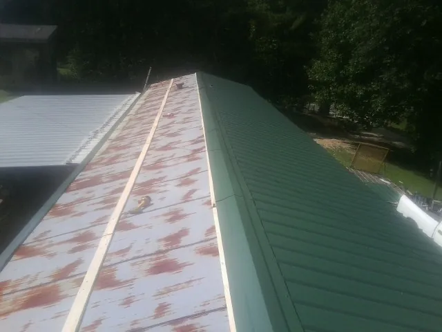 Old rusted panels beside newly installed green metal roofing — Wind Damage Roof Repair by Roofing Brothers in Highspire