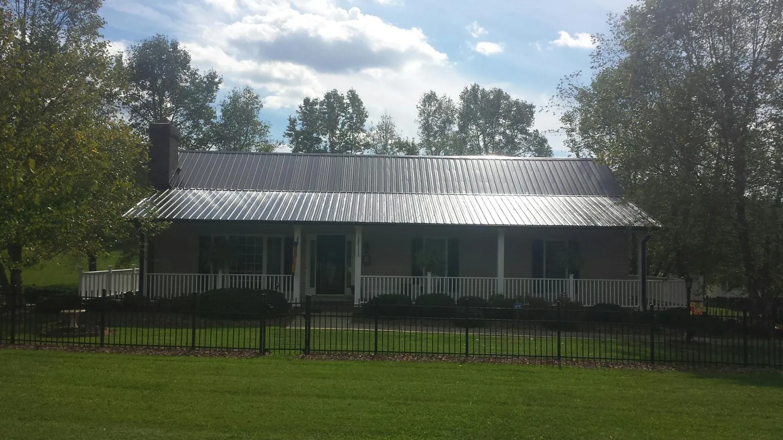 Gray metal roof on a brick ranch with a full width front porch — Gutter Guard Installation work by our crew in Highspire