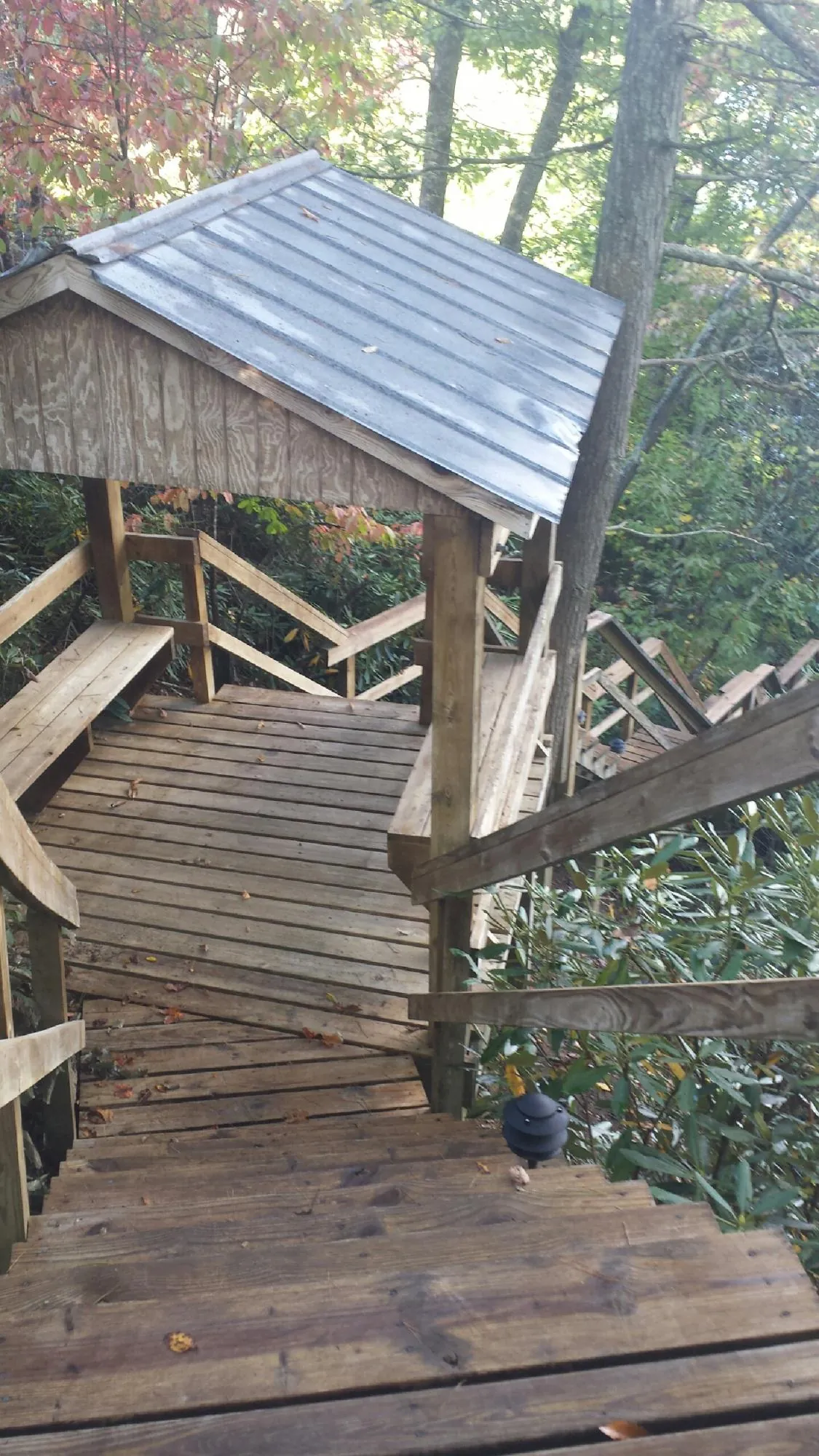Metal roofed shelter over wooden steps on a wooded walkway — Skylight Repair & Installation work by our crew in Highspire