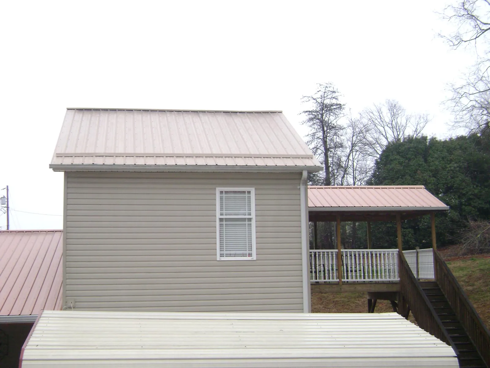 Tan metal roofs on a two story addition and attached porch, from a Roof Replacement job in Highspire