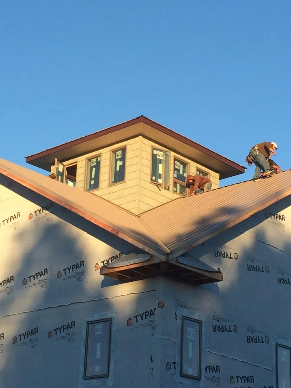 Roofers working around a rooftop cupola on a new metal roof at sunset — Roof Waterproofing in Highspire by Roofing Brothers